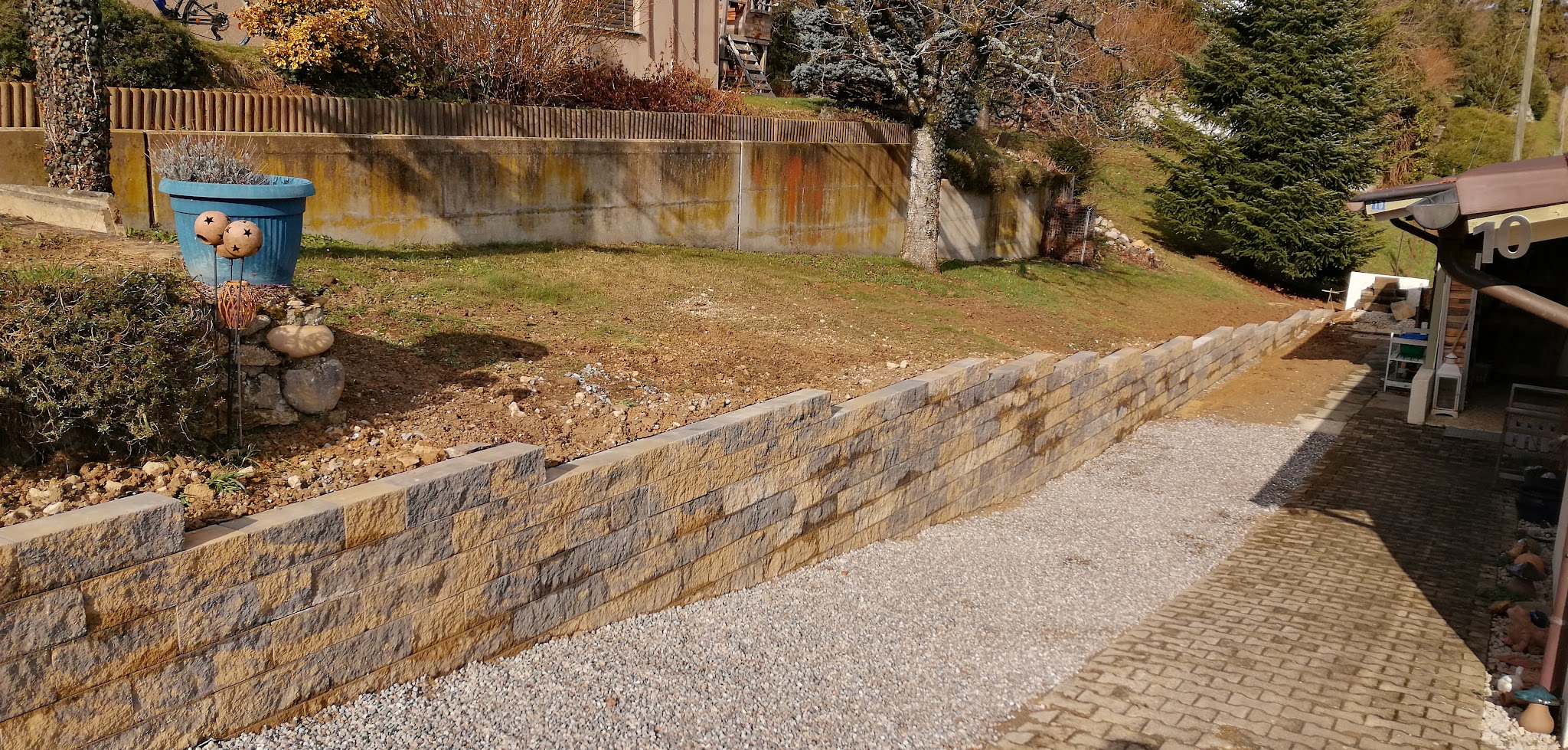 Neu erstellte Natursteinmauer an einem abschüssigen Garten