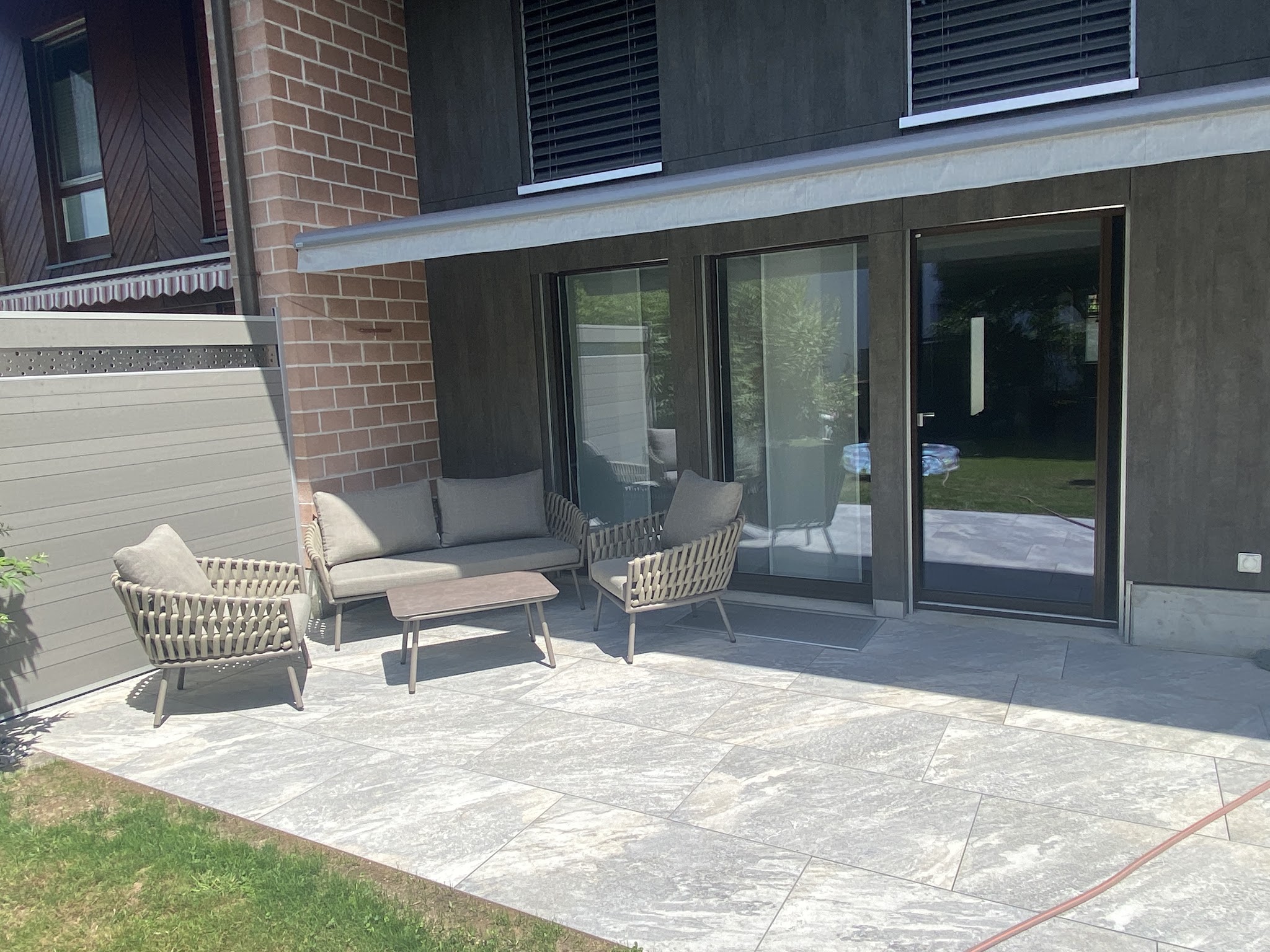 Terrasse mit Lounge-Möbeln vor einem modernen Wohnhaus